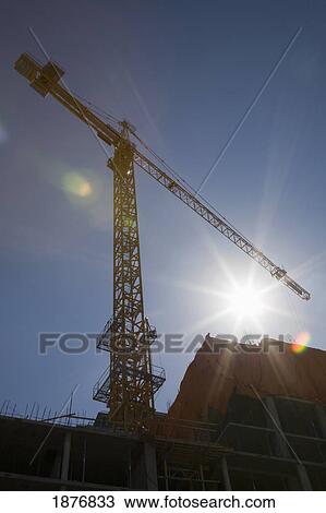 Stock Image - Calgary, Alberta, Canada; Silhouetted Building Crane With A Sunburst. Fotosearch
