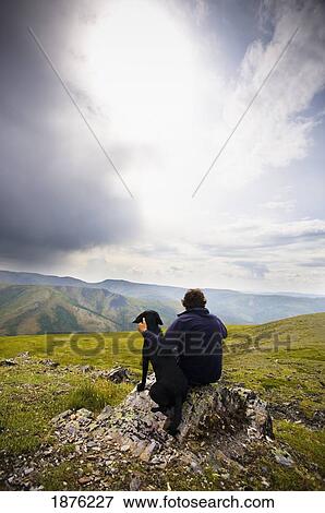 Dawson City, Yukon Territory, Canada; A Man And His Dog By The Top Of The World Highway Connecting Yukon Territory To Alaska View Large Photo Image Stock Photo - Dawson City, Yukon Territory, Canada; A Man And His Dog By The Top Of The World Highway Connecting Yukon Territory To Alaska. Fotosearch