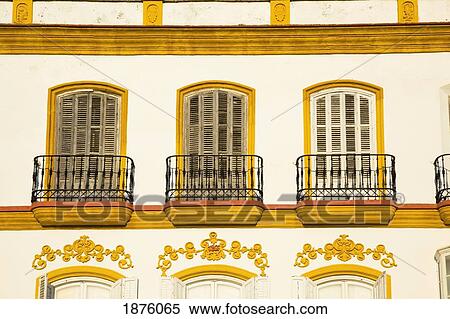 Stock Photography - Medina Sidonia, Andalusia, Spain; A White House With Windows And Ledges Trimmed In Gold. Fotosearch