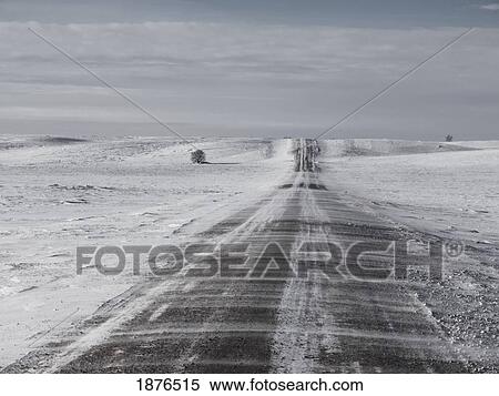 Stock Photography - Morden, Manitoba, Canada; Snow Blowing Over A Gravel Road In Southern Manitoba. Fotosearch