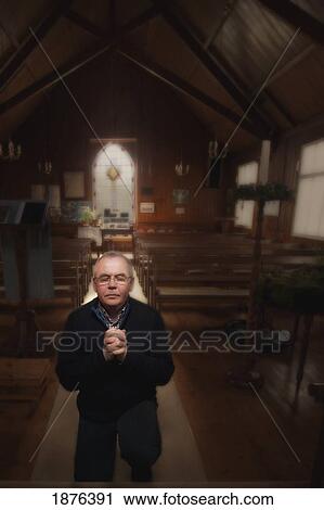 Stock Image - Northumberland, England; A Man On His Knees Praying At The Altar Of A Church. Fotosearch