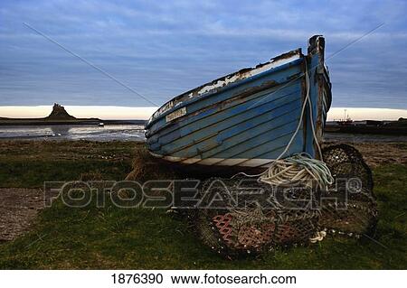 Northumberland, England; An Abandoned Boat And Traps On Shore With A View Of Lindisfarne (Holy Island) View Large Photo Image Stock Image - Northumberland, England; An Abandoned Boat And Traps On Shore With A View Of Lindisfarne (Holy Island). Fotosearch