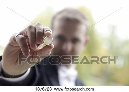 Stock Image - Ontario, Canada; A Groom Holds His Wedding Ring. Fotosearch