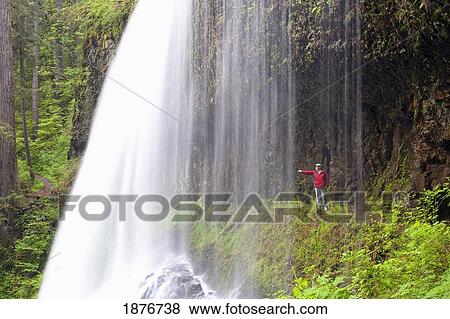 Stock Photo - Oregon, United States Of America; A Person Reaching Out To Touch As They Stand Behind North Middle Falls In Silver Falls State Park. Fotosearch