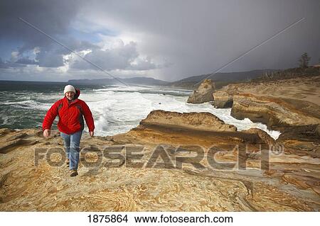 Picture - Pacific City, Oregon, United States Of America; A Man Walking Along The Coast At Cape Kiwanda. Fotosearch