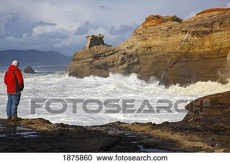 Stock Image - Pacific City, Oregon, United States Of America; A Man Looking Out Over The Coast At Cape Kiwanda. Fotosearch