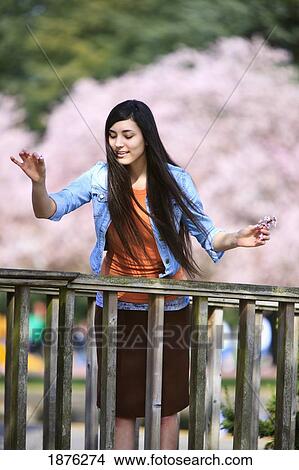 Portland, Oregon, United States Of America; A Teenage Girl Throwing Flower Petals Over A Railing In Portland Park View Large Photo Image Picture - Portland, Oregon, United States Of America; A Teenage Girl Throwing Flower Petals Over A Railing In Portland Park. Fotosearch