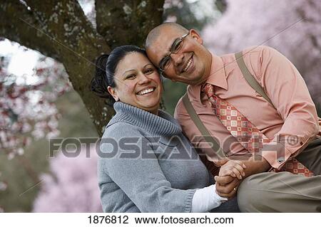 Stock Image - Portland, Oregon, United States Of America; A Couple Sitting Under A Cherry Blossom Tree In Spring. Fotosearch