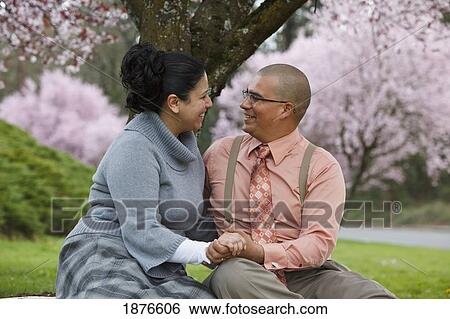 Stock Photograph - Portland, Oregon, United States Of America; A Couple Sitting Under A Cherry Blossom Tree In Spring In Westmorland Park. Fotosearch