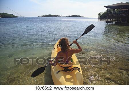 Stock Image - Roatan, Bay Islands, Honduras; A Young Woman Paddling A Kayak At Anthony's Key Resort. Fotosearch