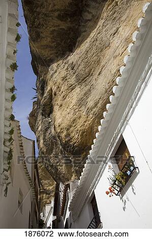 Stock Image - Setenil De Las Bodegas, Andalusia, Spain; White Houses Along The Street Underneath A Rock Cliff. Fotosearch