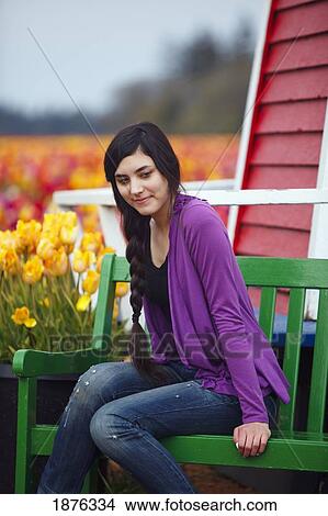 Picture - Woodburn, Oregon, United States Of America; A Teenage Girl Sits On A Bench Beside A Tulip Field At Wooden Shoe Tulip Farm. Fotosearch