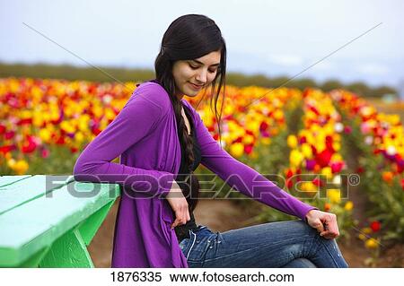 Stock Photography - Woodburn, Oregon, United States Of America; A Teenage Girl Sits On At A Picnic Table Beside A Tulip Field At Wooden Shoe Tulip Farm. Fotosearch