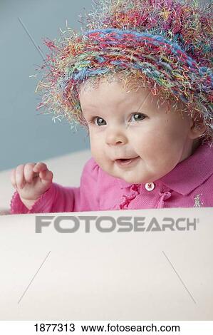 Stock Image - a baby girl wearing a colorful hat. Fotosearch
