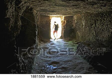 Stock Photo - a person walking through a tomb near the greek amphitheatre; syracuse, sicily, italy. Fotosearch