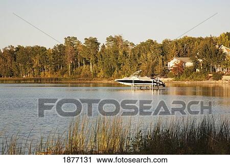 Stock Image - alberta, canada; a speed boat on a lift in a lake. Fotosearch