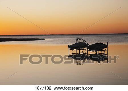 alberta, canada; silhouette of two boats on lifts in a lake at sunset View Large Photo Image Stock Image - alberta, canada; silhouette of two boats on lifts in a lake at sunset. Fotosearch