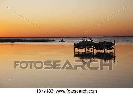 alberta, canada; silhouette of two boats on lifts in a lake at sunset View Large Photo Image Stock Image - alberta, canada; silhouette of two boats on lifts in a lake at sunset. Fotosearch