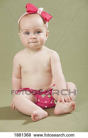 Stock Photo - baby girl sitting with a bow in her hair. Fotosearch