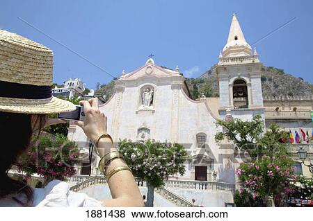 Stock Photo - female tourist taking a picture of san giuseppe church; taormina, sicily, italy. Fotosearch