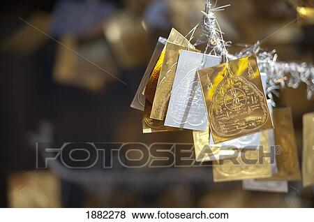 Stock Photo - gold and silver merit symbols hanging in doi kham buddhist temple; chiang mai, thailand. Fotosearch