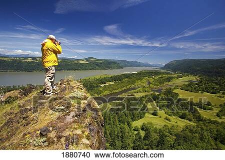 Stock Image - hiker taking pictures at a viewpoint in columbia river gorge national scenic area; oregon, united states of america. Fotosearch