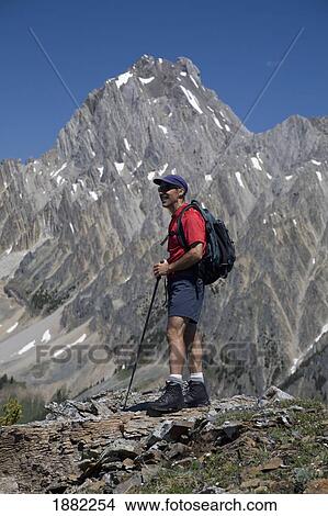 Picture - male hiker standing on top of a ridge with a mountain in the background; alberta, canada. Fotosearch