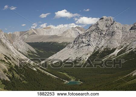 Stock Image - mountain lake in a valley with blue sky and clouds; alberta, canada. Fotosearch