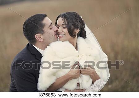 Stock Image - ontario, canada; a bride and groom holding each other closely while standing in a field. Fotosearch