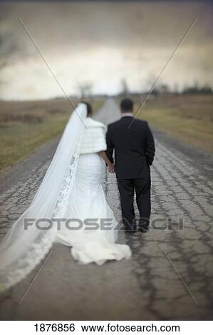 Stock Photograph - ontario, canada; a bride and groom walking down a road together. Fotosearch