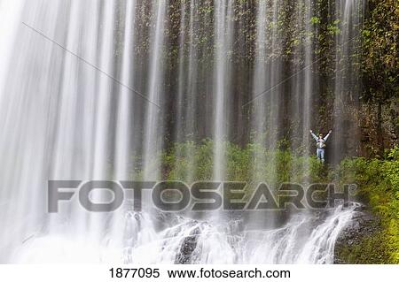 Stock Photography - oregon, united states of america; a person with arms raised behind north middle falls in silver falls state park. Fotosearch