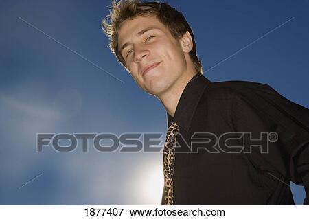 Stock Photo - portrait of a young businessman against a blue sky. Fotosearch