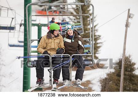 Stock Photo - red deer, alberta, canada; a man and woman riding a chair lift at a ski area. Fotosearch