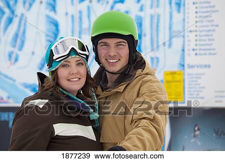 Stock Photo - red deer, alberta, canada; a man and woman wearing a helmet and ski mask at a ski area. Fotosearch