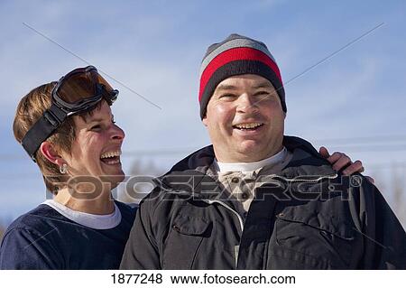 Stock Photo - red deer, alberta, canada; a man and woman laughing together wearing a toque and ski mask. Fotosearch