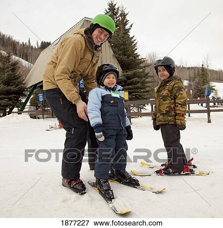 red deer, alberta, canada; a man with two young boys wearing skis and helmets at a ski area View Large Photo Image Stock Photo - red deer, alberta, canada; a man with two young boys wearing skis and helmets at a ski area. Fotosearch