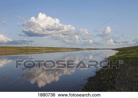Stock Photograph - red river floodway with clouds reflected in the water; winnipeg, manitoba, canada. Fotosearch