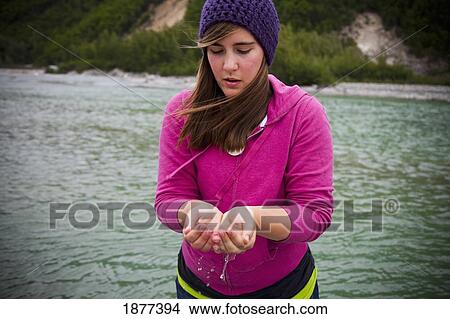 Picture - skagway, alaska, united states of america; a young woman holding clean water from the river in her cupped hands. Fotosearch