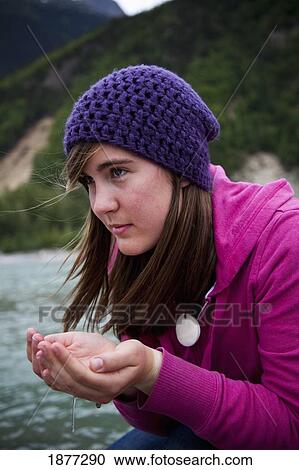 Stock Image - skagway, alaska, united states of america; a young woman cups her hands and drinks water from a river. Fotosearch