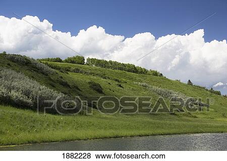 storm clouds over the hillside approaching a lake in a park; calgary, alberta, canada View Large Photo Image Stock Photo - storm clouds over the hillside approaching a lake in a park; calgary, alberta, canada. Fotosearch