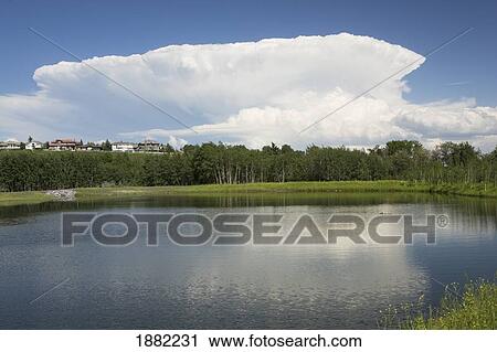 Stock Image - storm clouds reflecting on a lake in a park; calgary, alberta, canada. Fotosearch
