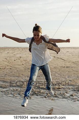 Picture - tarifa, cadiz, andalusia, spain; a girl jumps over the water on los lances beach along costa de la luz. Fotosearch