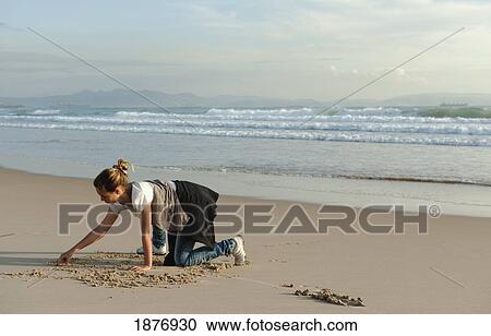 Stock Image - tarifa, cadiz, andalusia, spain; a girl drawing in the sand at los lances beach along costa de la luz. Fotosearch