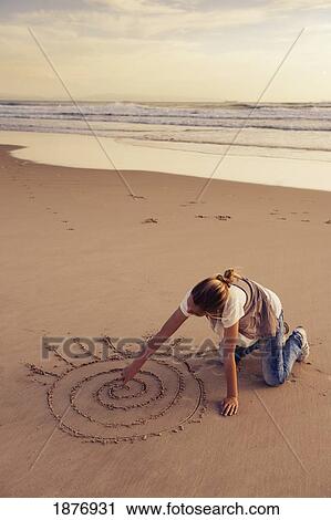 Stock Image - tarifa, cadiz, andalusia, spain; a girl drawing in the sand at los lances beach along costa de la luz. Fotosearch