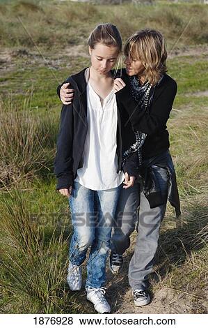 Stock Photo - tarifa, cadiz, andalusia, spain; a mother comforts her daughter as they walk together. Fotosearch
