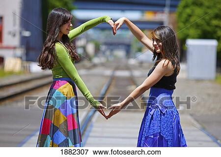 Stock Photo - teenage girls forming a heart with their arms; portland, oregon, united states of america. Fotosearch