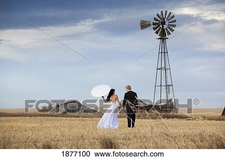 three hills, alberta, canada; a bride and groom walking through a farm field View Large Photo Image Stock Image - three hills, alberta, canada; a bride and groom walking through a farm field. Fotosearch