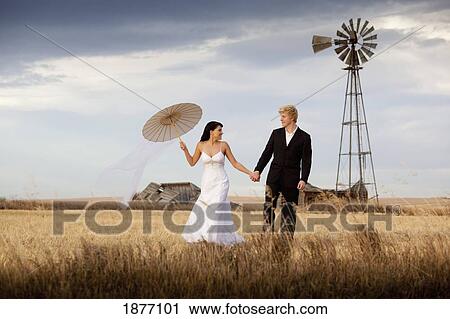 three hills, alberta, canada; a bride and groom walking through a farm field View Large Photo Image Stock Image - three hills, alberta, canada; a bride and groom walking through a farm field. Fotosearch