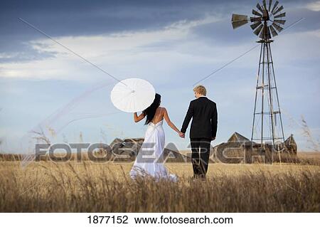 three hills, alberta, canada; a bride and groom walking across farm land View Large Photo Image Stock Image - three hills, alberta, canada; a bride and groom walking across farm land. Fotosearch