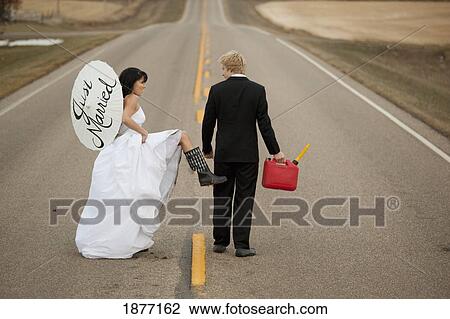 three hills, alberta, canada; a bride and groom walk down a rural road with a jerry can and a parasol saying 'just married' View Large Photo Image Stock Image - three hills, alberta, canada; a bride and groom walk down a rural road with a jerry can and a parasol saying 'just married'. Fotosearch